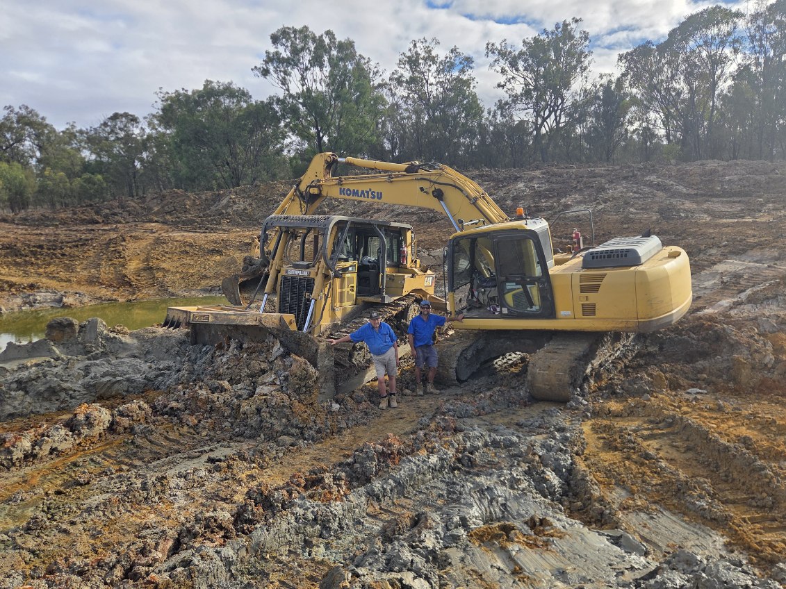 Tyrone and his dad in front of Komatsu excavator and CAT D6T dozer working a bushland dam