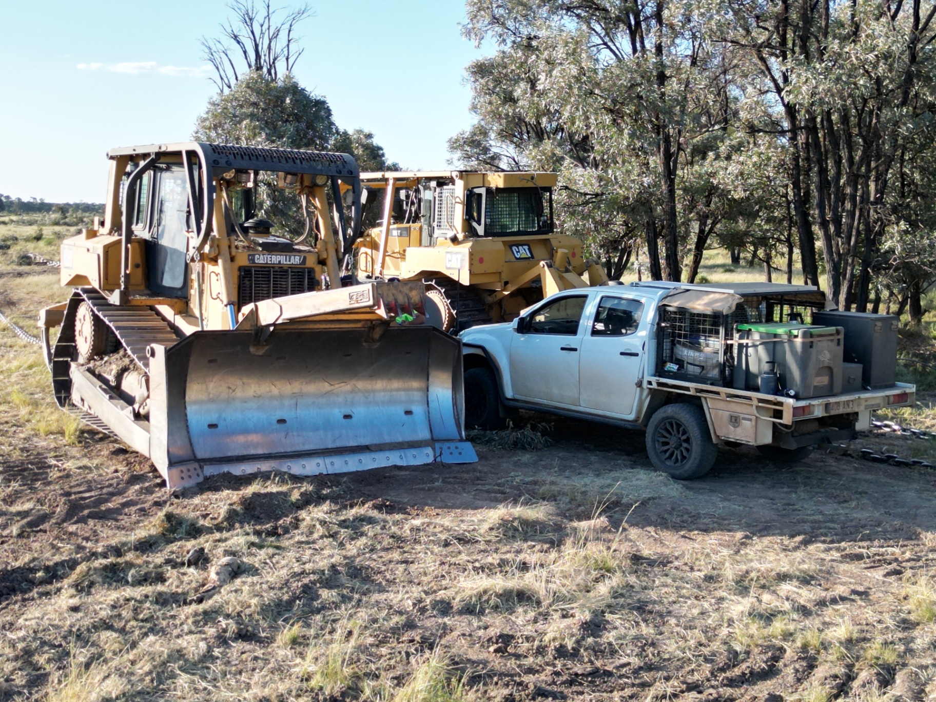 Two CAT dozers parked beside a work ute on a rural job