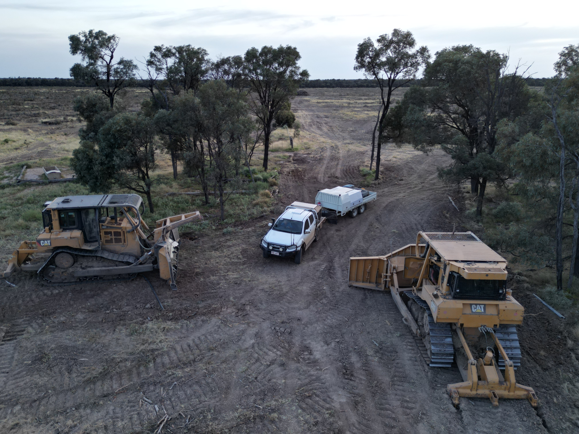 Aerial drone view of dozers, scraper and ute lined up on a fresh-cut track