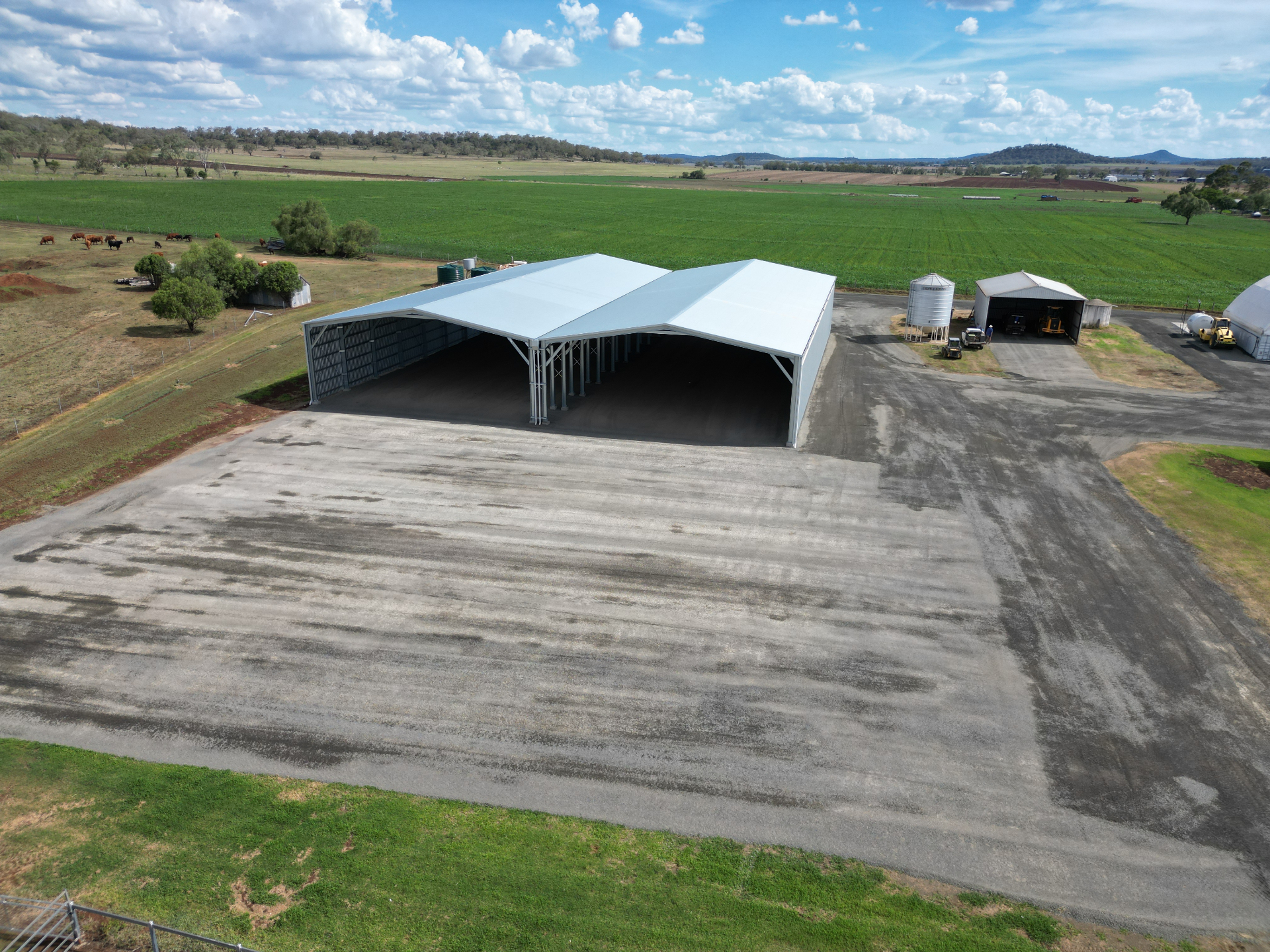 Aerial view of a large white-roof machinery shed surrounded by gravel hardstand showing colour variation as it cures